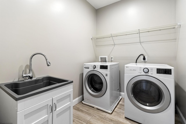 washroom featuring separate washer and dryer, baseboards, wood finish floors, cabinet space, and a sink