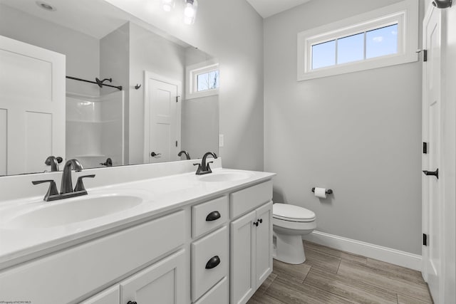bathroom with a shower, baseboards, a sink, and toilet