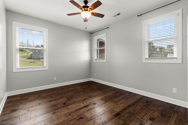 unfurnished room featuring dark wood-style flooring, baseboards, a ceiling fan, and visible vents