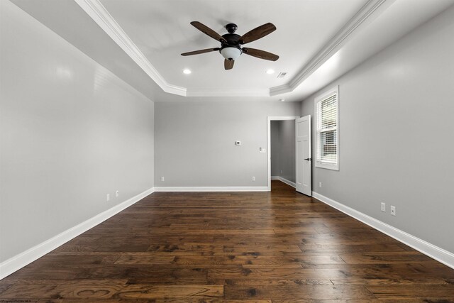 empty room featuring ceiling fan, dark wood finished floors, crown molding, a tray ceiling, and recessed lighting