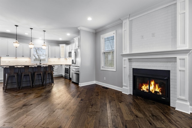 kitchen featuring white cabinets, dark wood-style flooring, light countertops, a breakfast bar, and stainless steel appliances