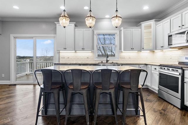 kitchen with appliances with stainless steel finishes, a sink, white cabinetry, and light stone countertops