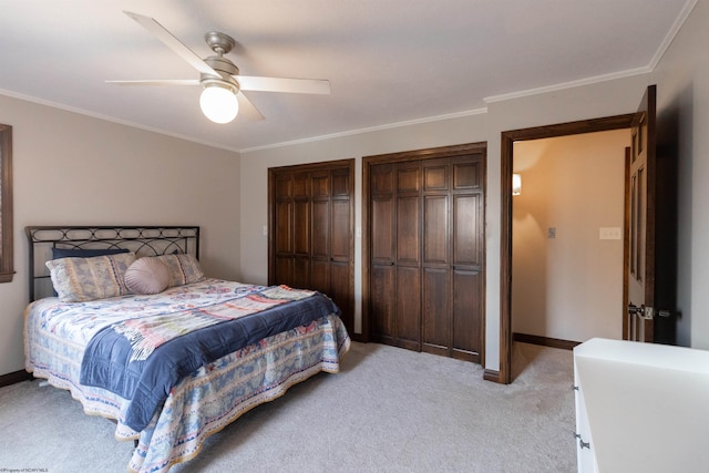 bedroom featuring light colored carpet, baseboards, crown molding, and multiple closets
