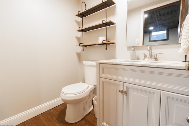 half bathroom featuring wood finished floors, baseboards, vanity, and toilet