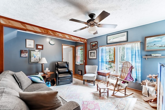 living room with ceiling fan, baseboards, wood finished floors, and a textured ceiling