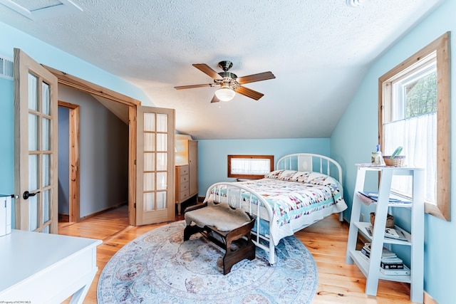 bedroom with light wood-type flooring, ceiling fan, a textured ceiling, and lofted ceiling