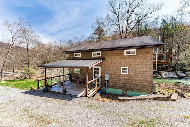exterior space with a wooden deck and a shingled roof