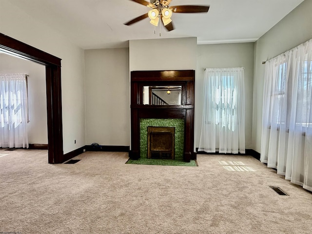 unfurnished living room featuring carpet floors, baseboards, a fireplace, and a ceiling fan