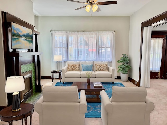 carpeted living room with baseboards, a fireplace, and ceiling fan