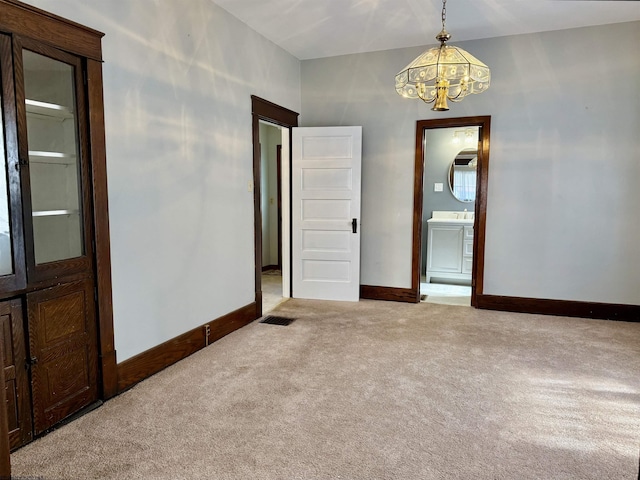 carpeted empty room with baseboards, a chandelier, and visible vents