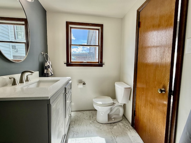 bathroom with marble finish floor, toilet, vanity, and baseboards