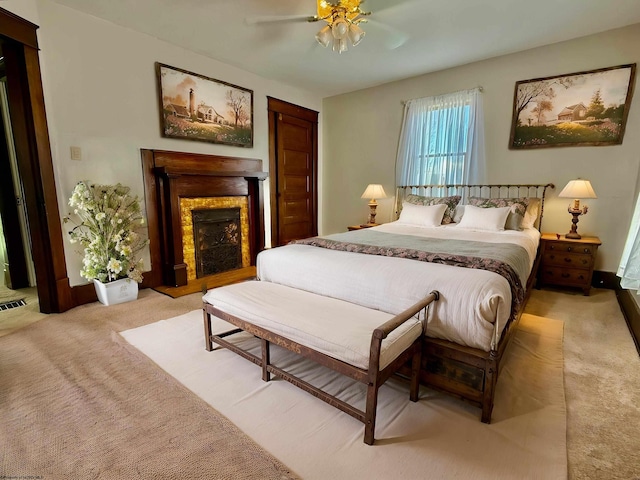 bedroom with a fireplace, ceiling fan, visible vents, and light carpet