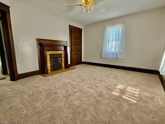 unfurnished living room with a fireplace with flush hearth, carpet floors, a ceiling fan, and baseboards