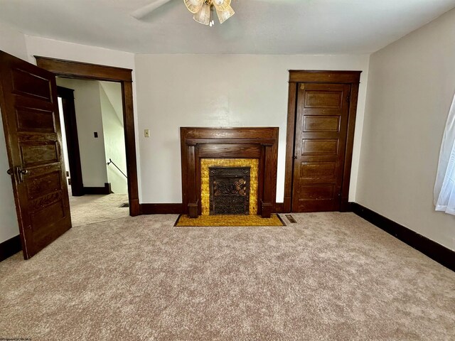 unfurnished living room with a fireplace with flush hearth, a ceiling fan, baseboards, and carpet floors