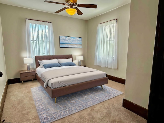 carpeted bedroom with ceiling fan and baseboards