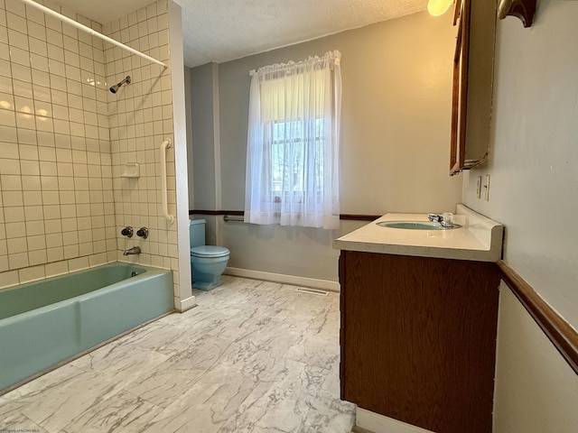 bathroom with marble finish floor, a textured ceiling, vanity, and toilet