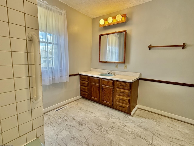 bathroom featuring marble finish floor, visible vents, vanity, baseboards, and a textured ceiling