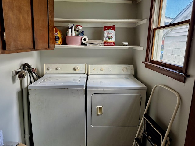 washroom featuring a wealth of natural light, washer and clothes dryer, and cabinet space