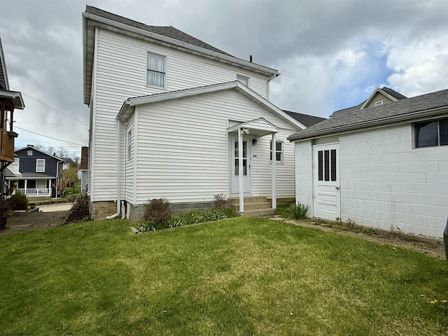 rear view of property with a lawn and entry steps