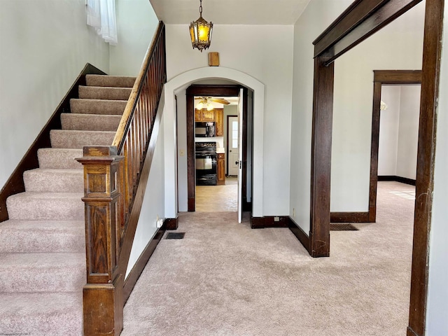 entrance foyer with arched walkways, baseboards, visible vents, carpet, and stairs