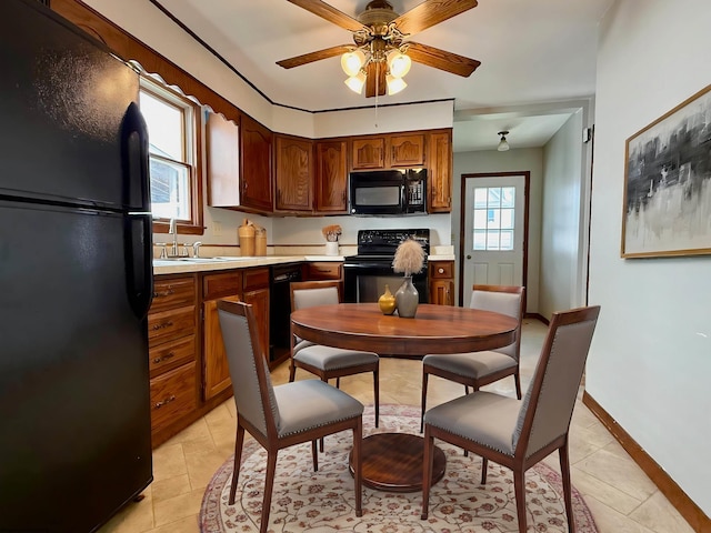 kitchen with a sink, light tile patterned flooring, a ceiling fan, light countertops, and black appliances