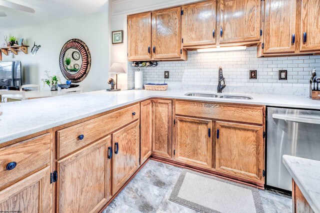 kitchen with stainless steel dishwasher, a sink, light stone countertops, decorative backsplash, and ceiling fan