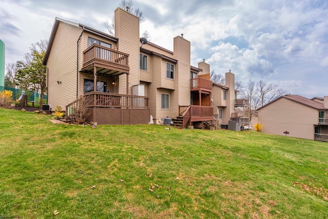 rear view of house featuring cooling unit, a lawn, and a balcony
