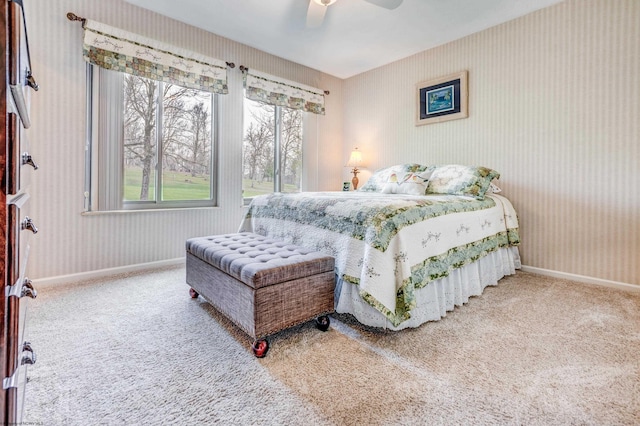 carpeted bedroom featuring baseboards, a ceiling fan, multiple windows, and wallpapered walls