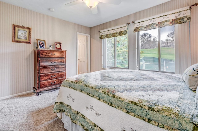 carpeted bedroom featuring wallpapered walls, a ceiling fan, and baseboards