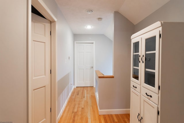 corridor featuring recessed lighting, vaulted ceiling, light wood finished floors, and baseboards