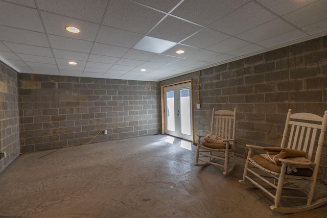 unfurnished room featuring concrete block wall, a paneled ceiling, and concrete flooring