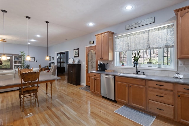 kitchen featuring dishwasher, light wood finished floors, decorative backsplash, and a sink
