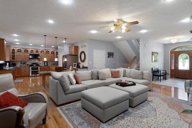 living room featuring stairway, a ceiling fan, light wood-style flooring, visible vents, and recessed lighting