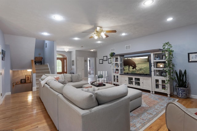 living room with stairway, ceiling fan, light wood finished floors, and visible vents