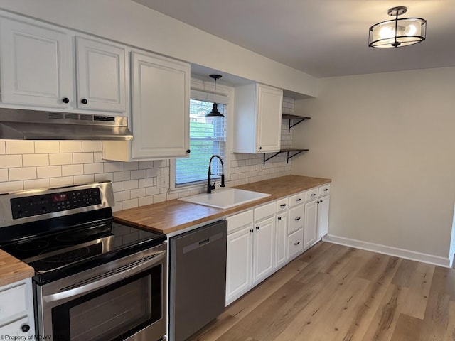 kitchen with stainless steel appliances, under cabinet range hood, a sink, and wooden counters