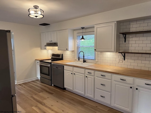 kitchen featuring open shelves, a sink, wooden counters, appliances with stainless steel finishes, and under cabinet range hood