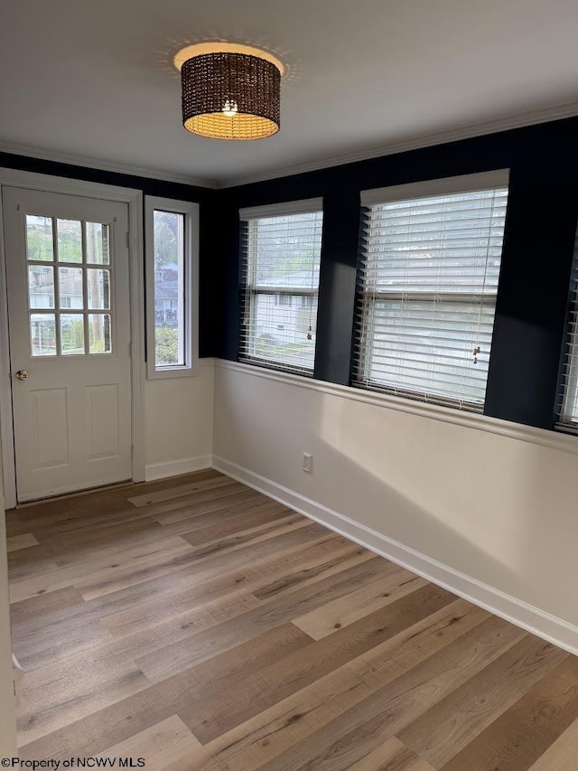 foyer entrance with wood finished floors, a wealth of natural light, and ornamental molding