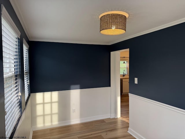 unfurnished room featuring wood finished floors, crown molding, and a sink
