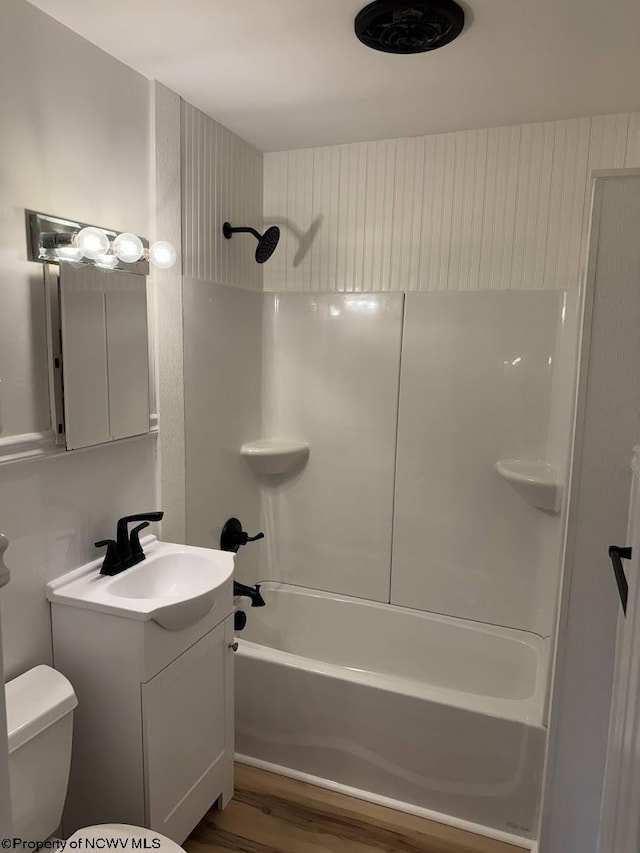 bathroom with washtub / shower combination, wood finished floors, toilet, and vanity
