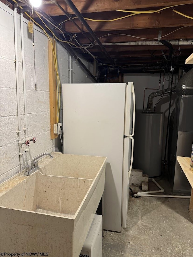 unfinished basement with water heater, a sink, and freestanding refrigerator