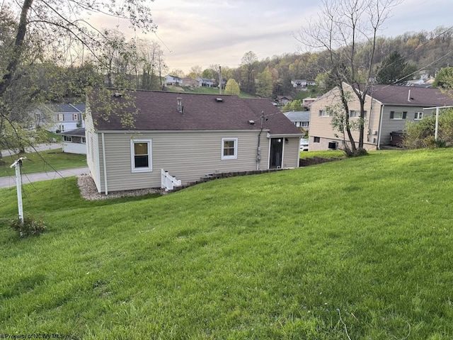 rear view of property with a yard, roof with shingles, and a residential view