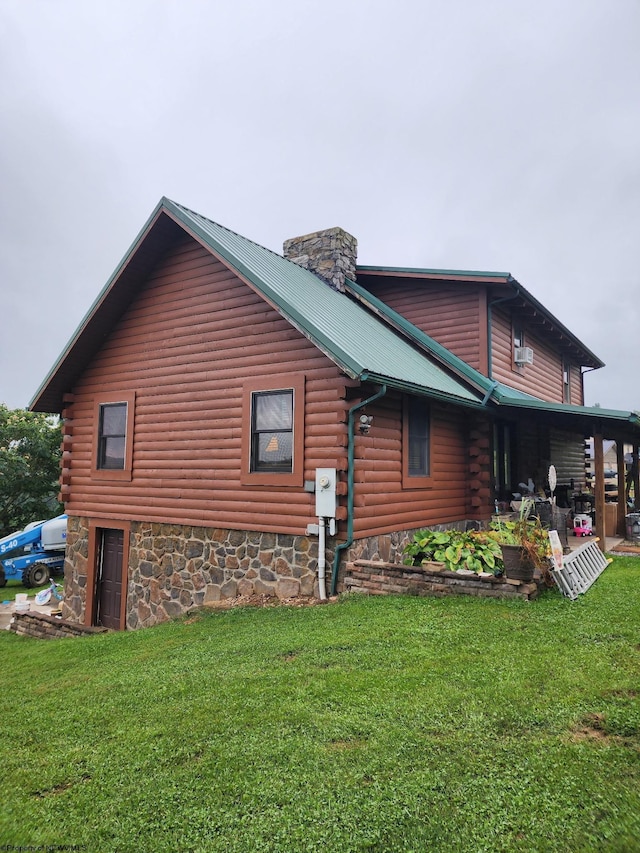view of home's exterior featuring log exterior, a chimney, a yard, and metal roof