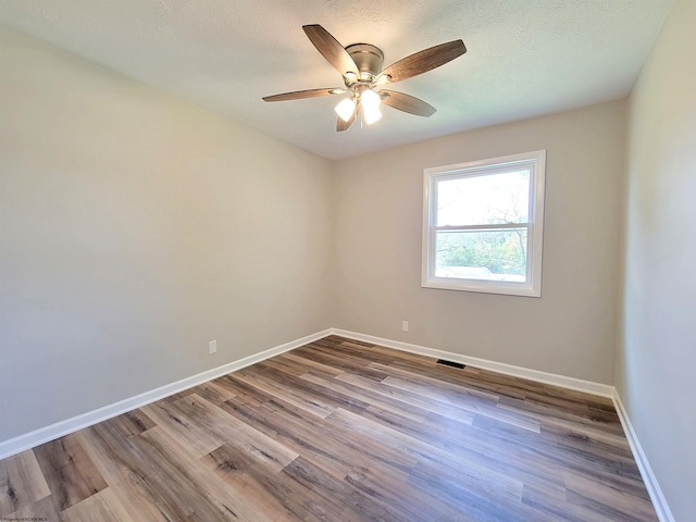 unfurnished room with baseboards, wood finished floors, and visible vents