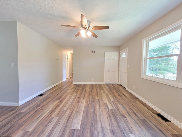 unfurnished room featuring baseboards, a ceiling fan, wood finished floors, and visible vents