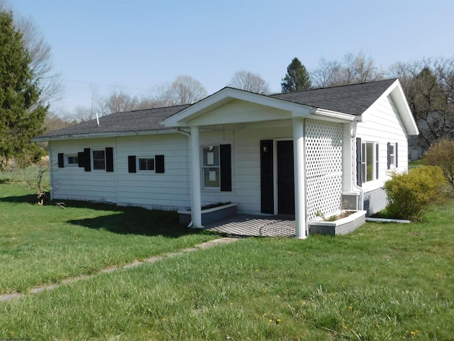 back of property with a yard and a shingled roof