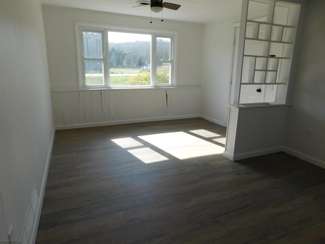 spare room featuring dark wood finished floors, baseboards, and ceiling fan