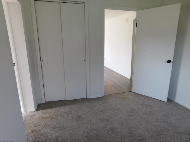 unfurnished bedroom featuring baseboards, carpet, and a closet
