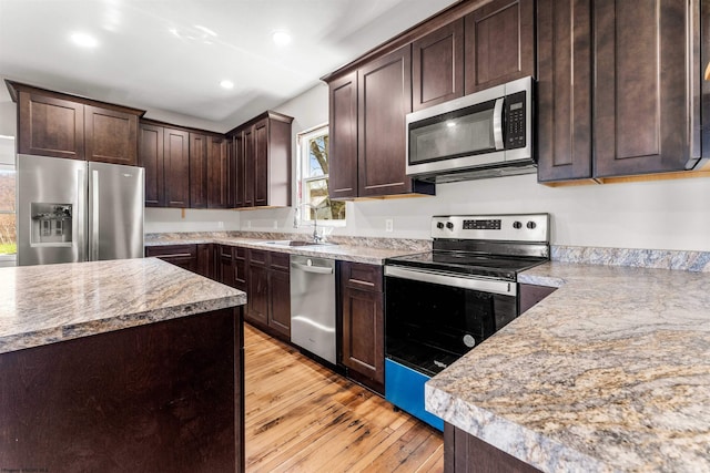 kitchen featuring dark brown cabinets, light wood-type flooring, stainless steel appliances, light countertops, and recessed lighting