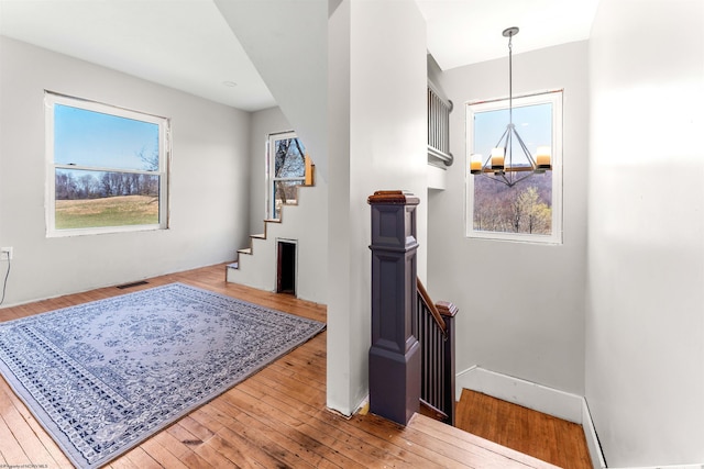 corridor with hardwood / wood-style flooring, an upstairs landing, and a healthy amount of sunlight