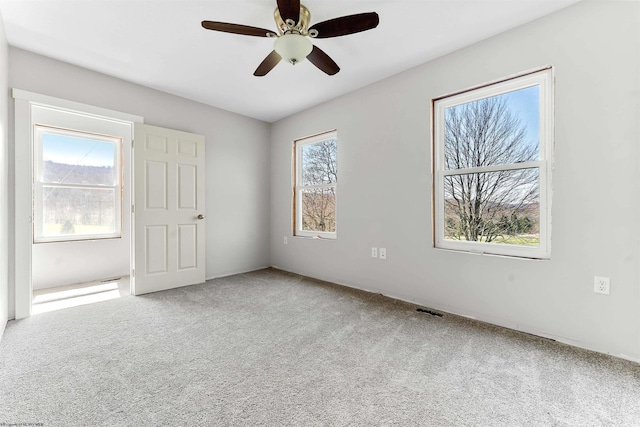 carpeted spare room with a ceiling fan and visible vents